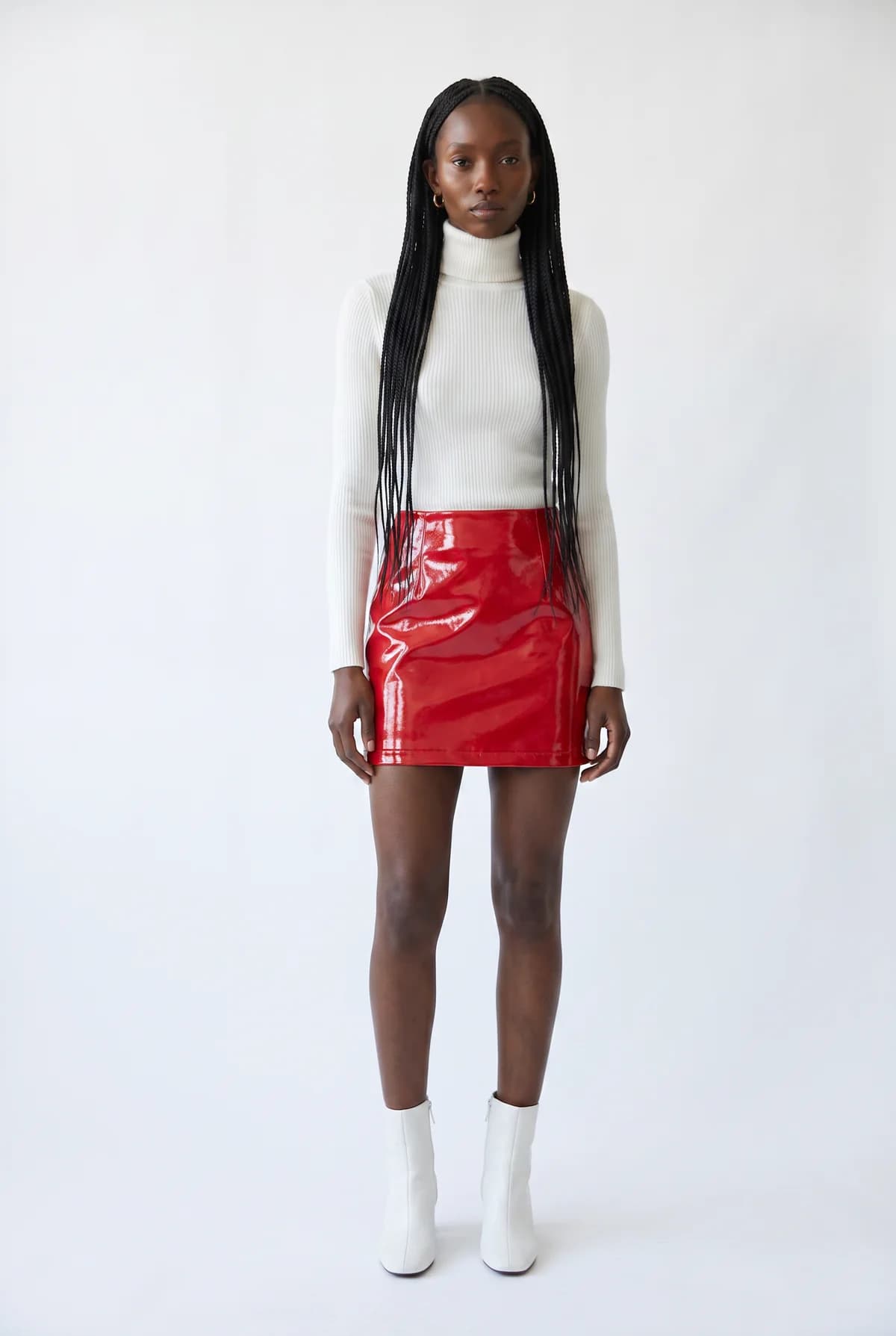 The same model restyled in a white turtleneck, red patent leather mini skirt, and white boots