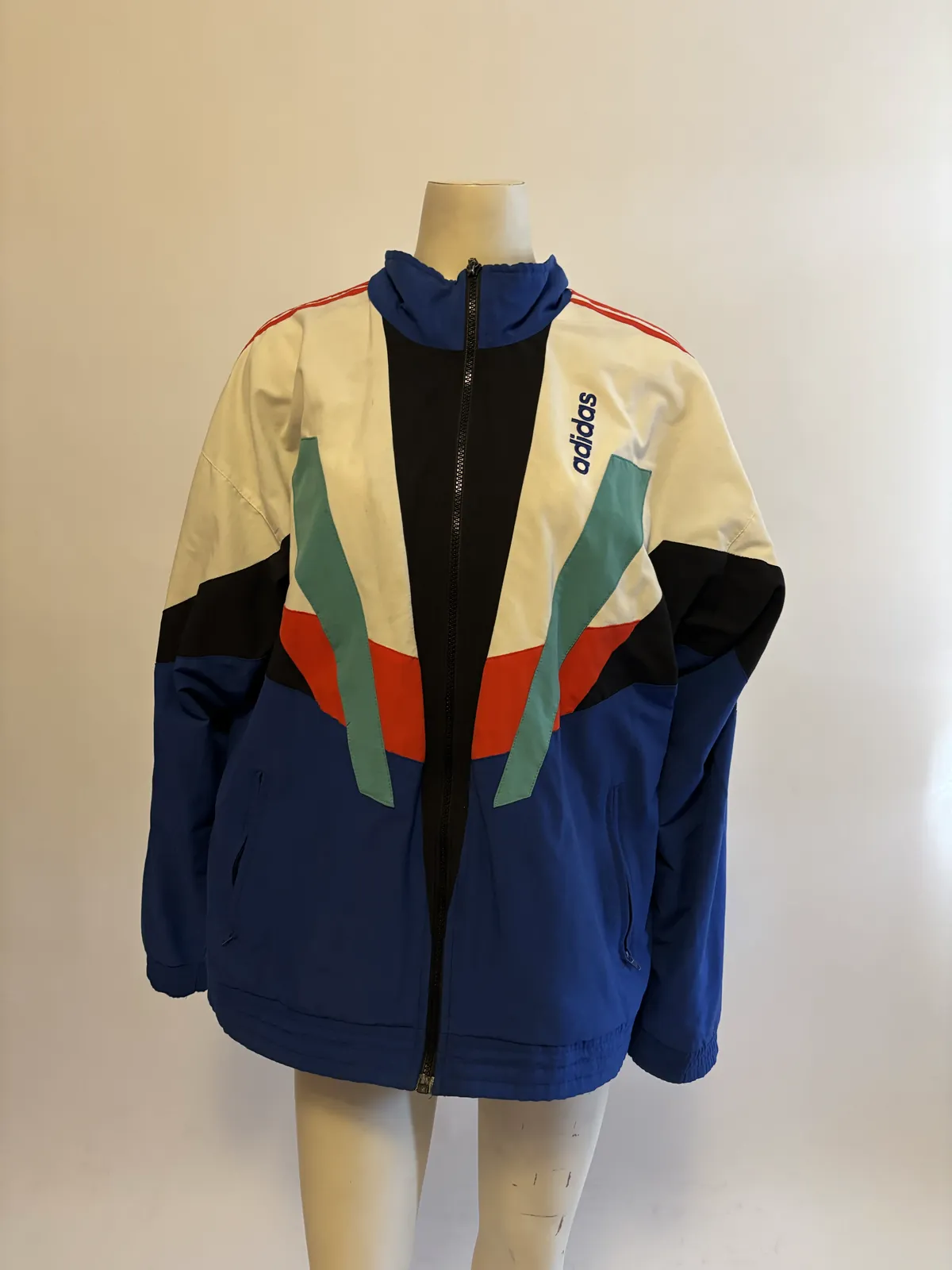 The jacket on a mannequin under warm light, with the white panels looking yellow