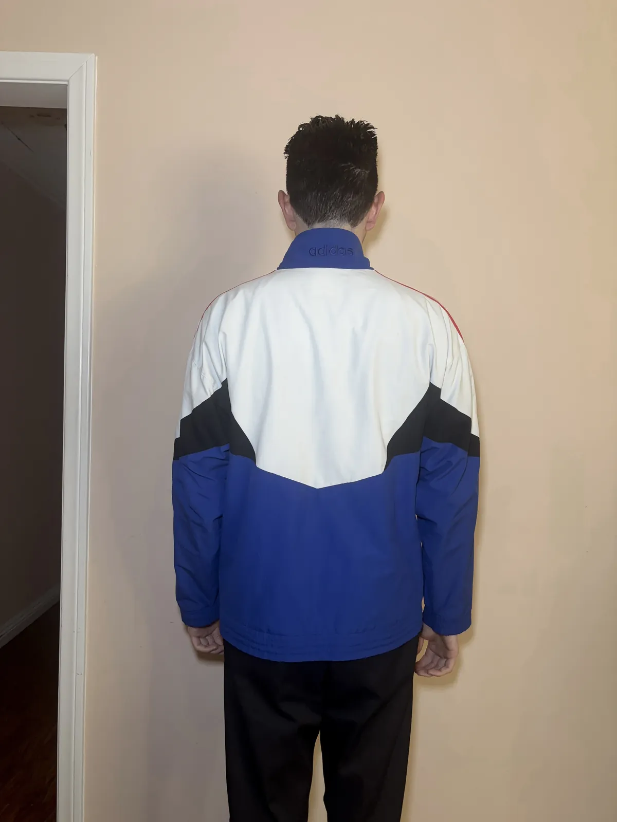The jacket worn by a person, back, with the collar up so the word on it shows