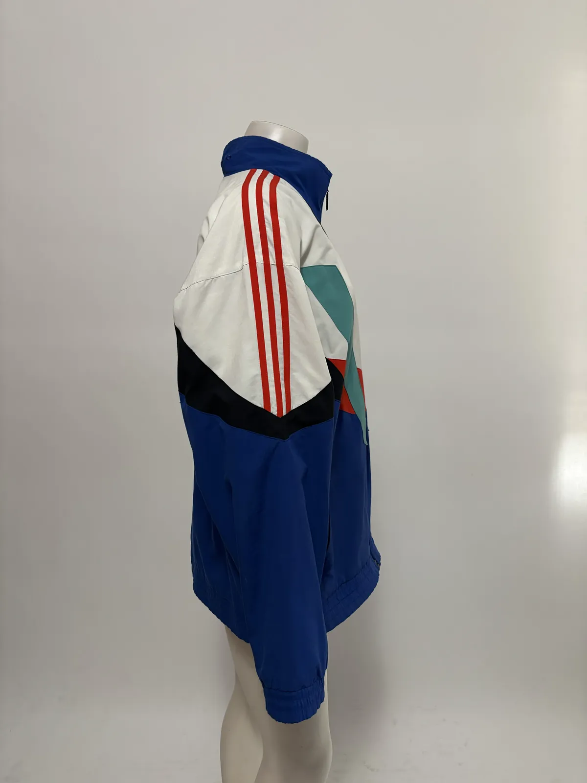 Product photo: the side of the track jacket on a mannequin, showing the sleeve stripes