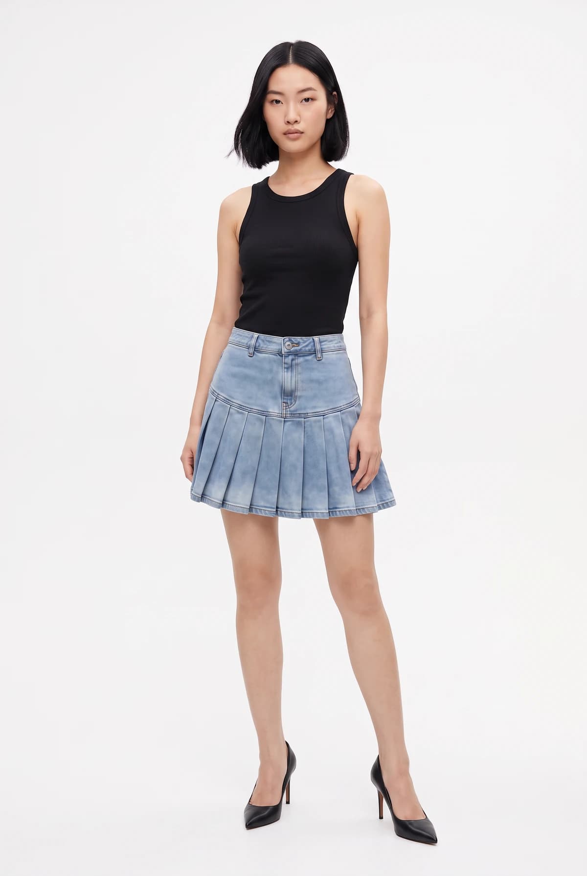 The model wearing the pleated denim skirt at her natural waist with her black tank top
