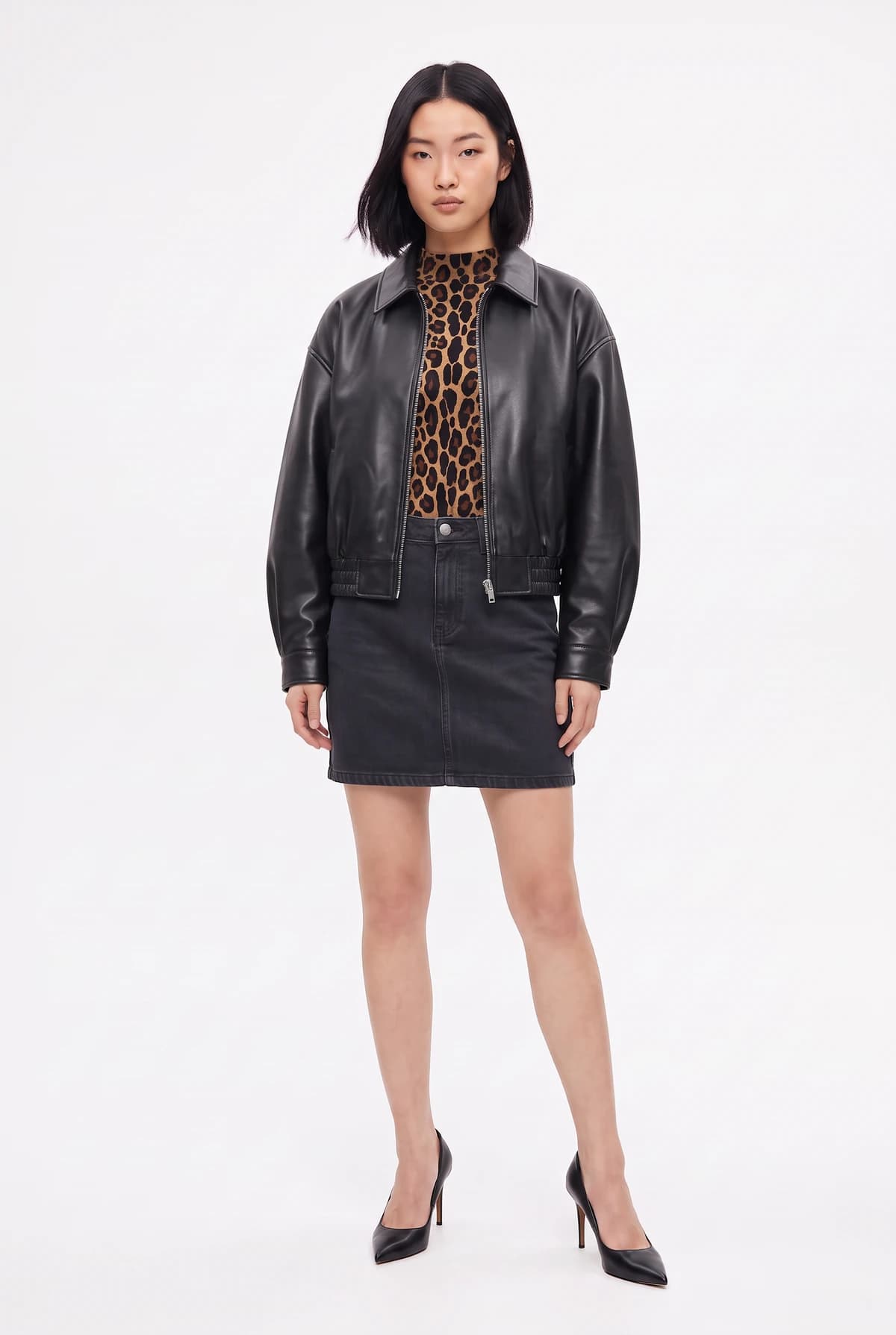 The model wearing the leather jacket open over the leopard print top and black skirt