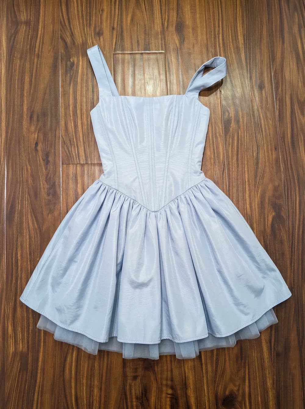 The light blue corset dress laid flat on a wooden floor