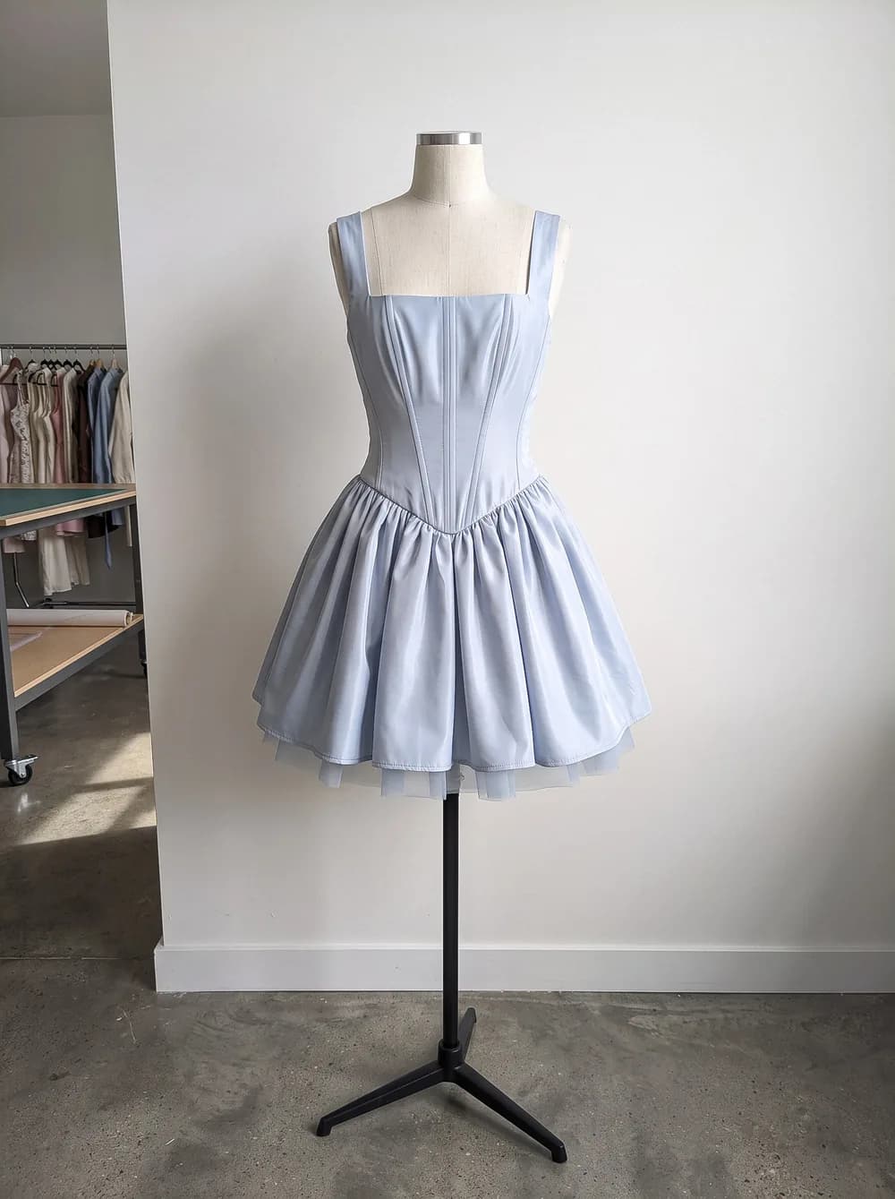 The light blue corset dress on a dress form in a workroom